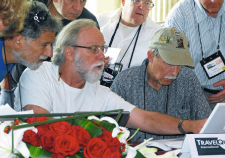 Surrounded by concerned travelers, Jay Anderson (TQ’s eclipse meteorologist) checks weather projections for eclipse day. (Photo by Judy Anderson)